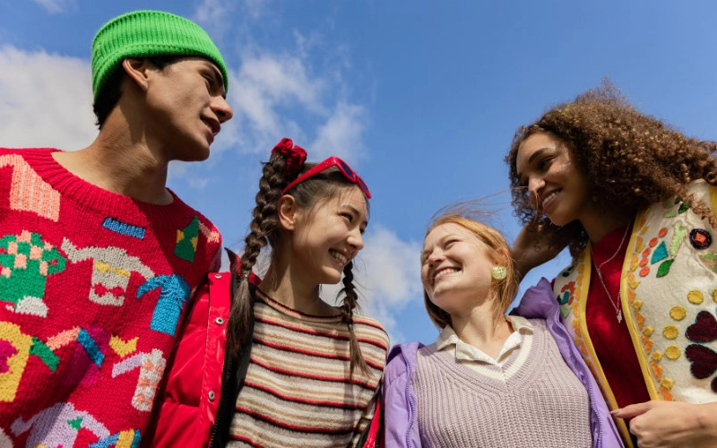 Four students chatting under a blue sky
