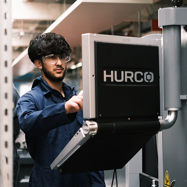 young person in overalls at control panel