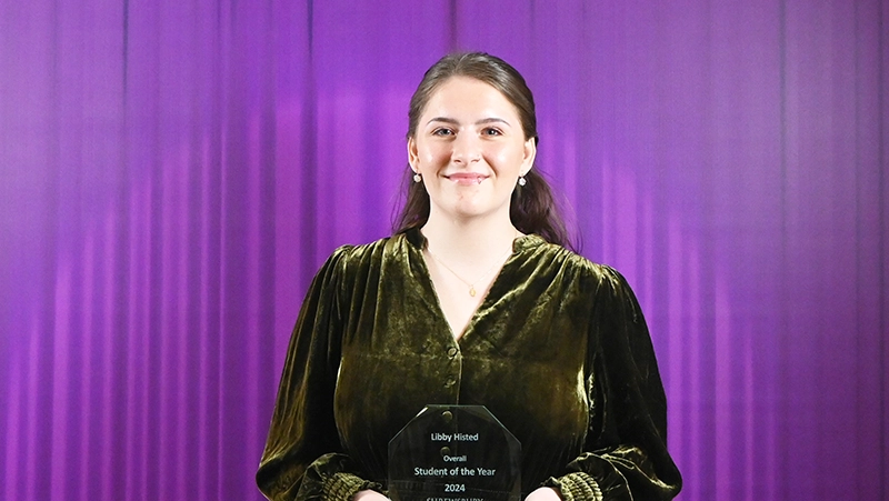 Student in front of a purple curtain