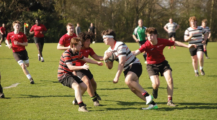 Group of students playing rugby on ppitch
