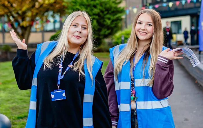 Two students wearing college branded vests