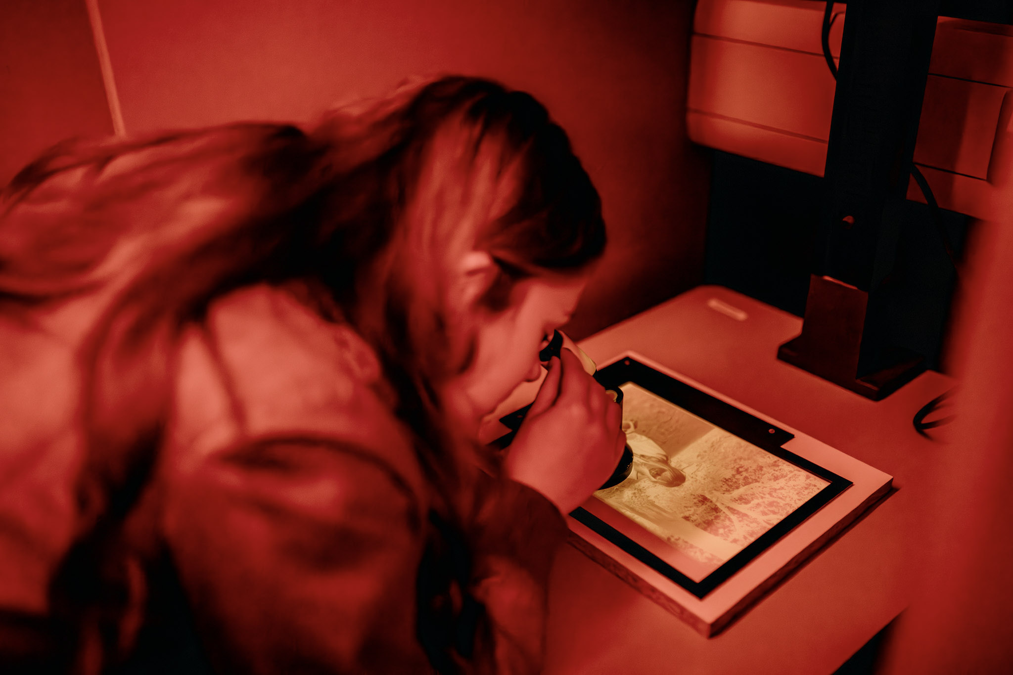 Student in darkroom checking print