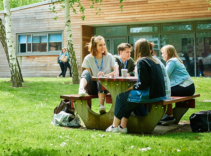 young students sitting at a bench outside